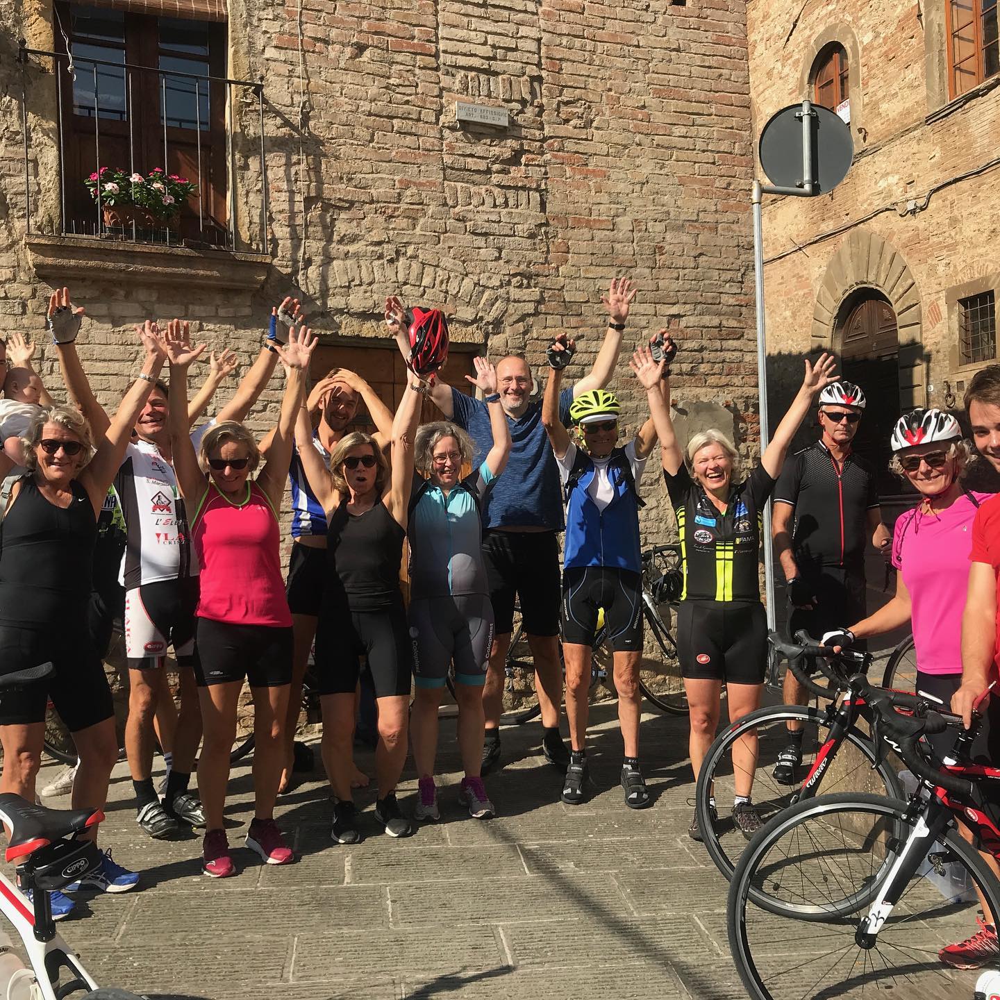 Glade cyklister poser foran murstensbygning