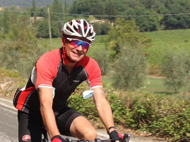 Mand cykler på landevej i solskinsvejr