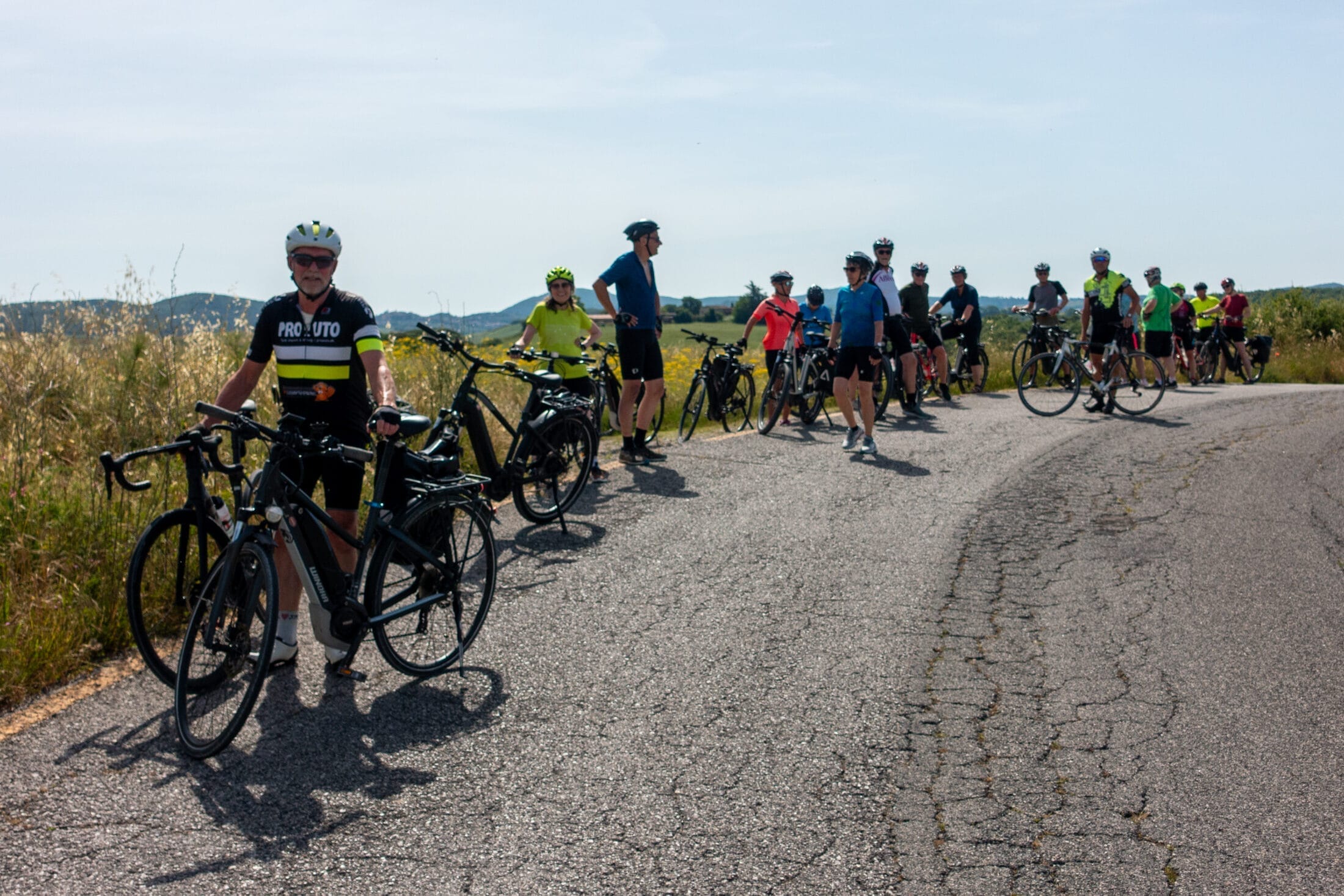 Gruppe cyklister holder pause på landevej i solskin